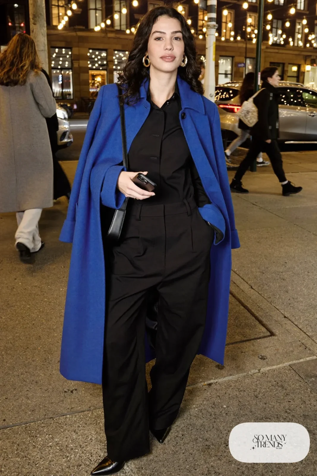Black wide-leg jumpsuit, oversized cobalt coat, black ankle boots, gold earrings, small bag, winter outfit 34