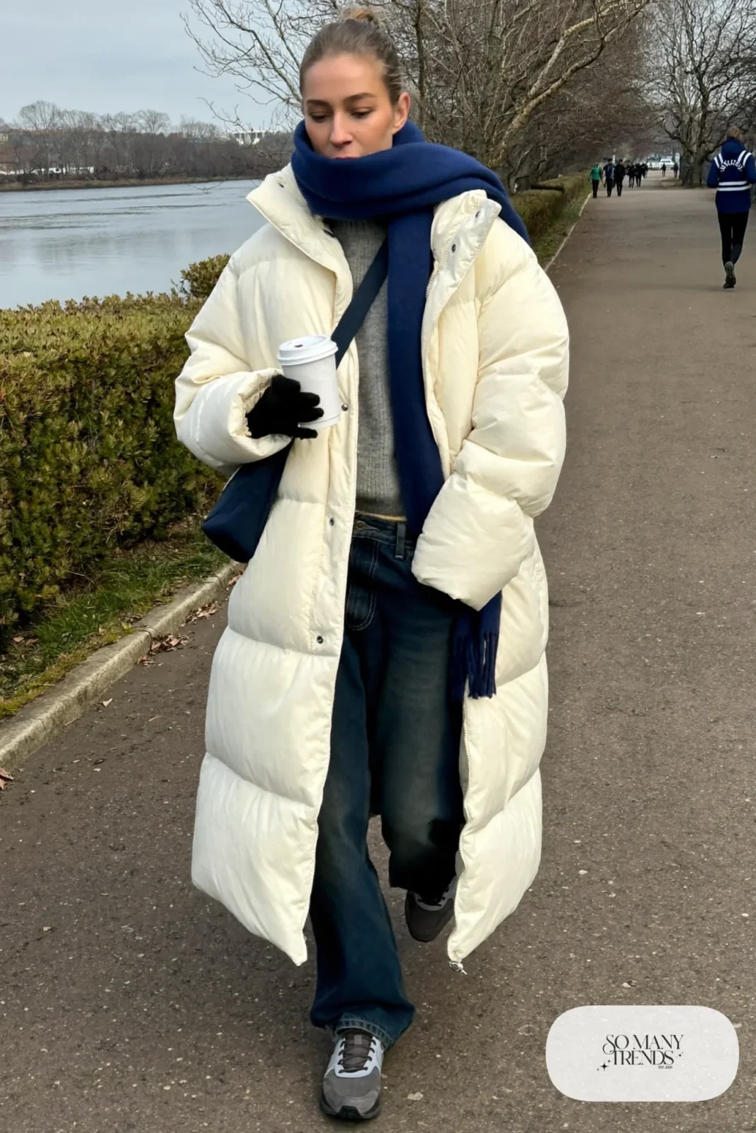 long cream puffer coat dark straight jeans gray knit sweater gray sneakers navy scarf crossbody bag outfit 11