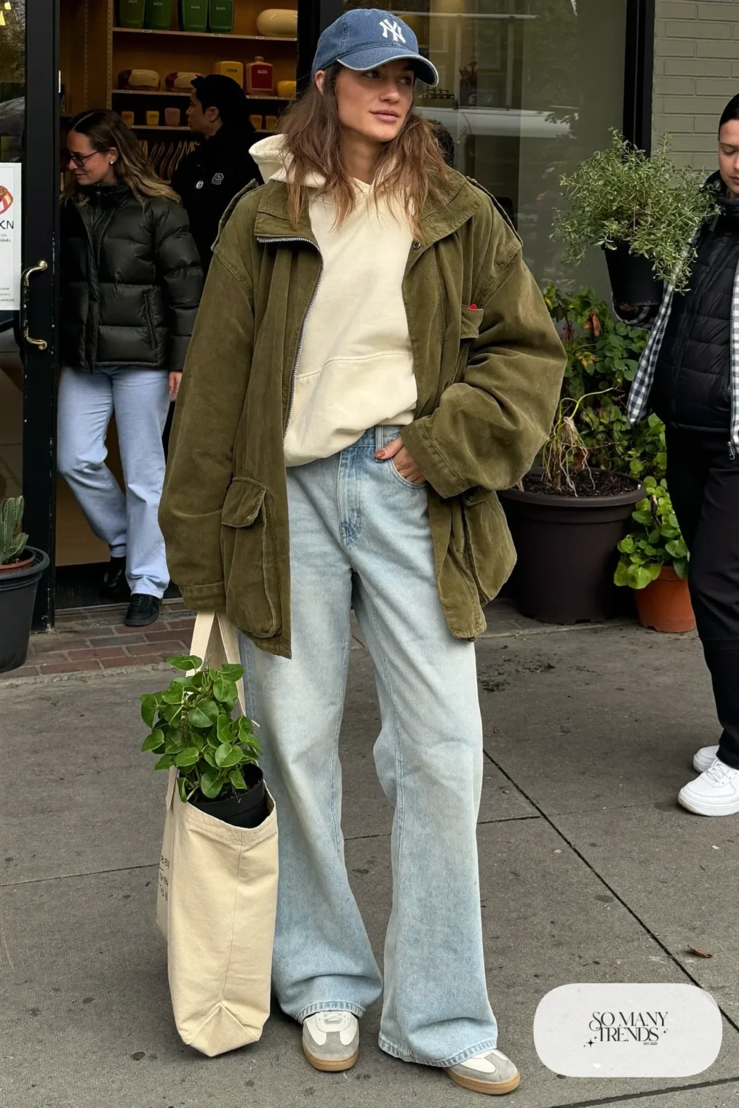 olive green field jacket cream hoodie light wash wide leg jeans white sneakers navy cap tote bag outfit 24