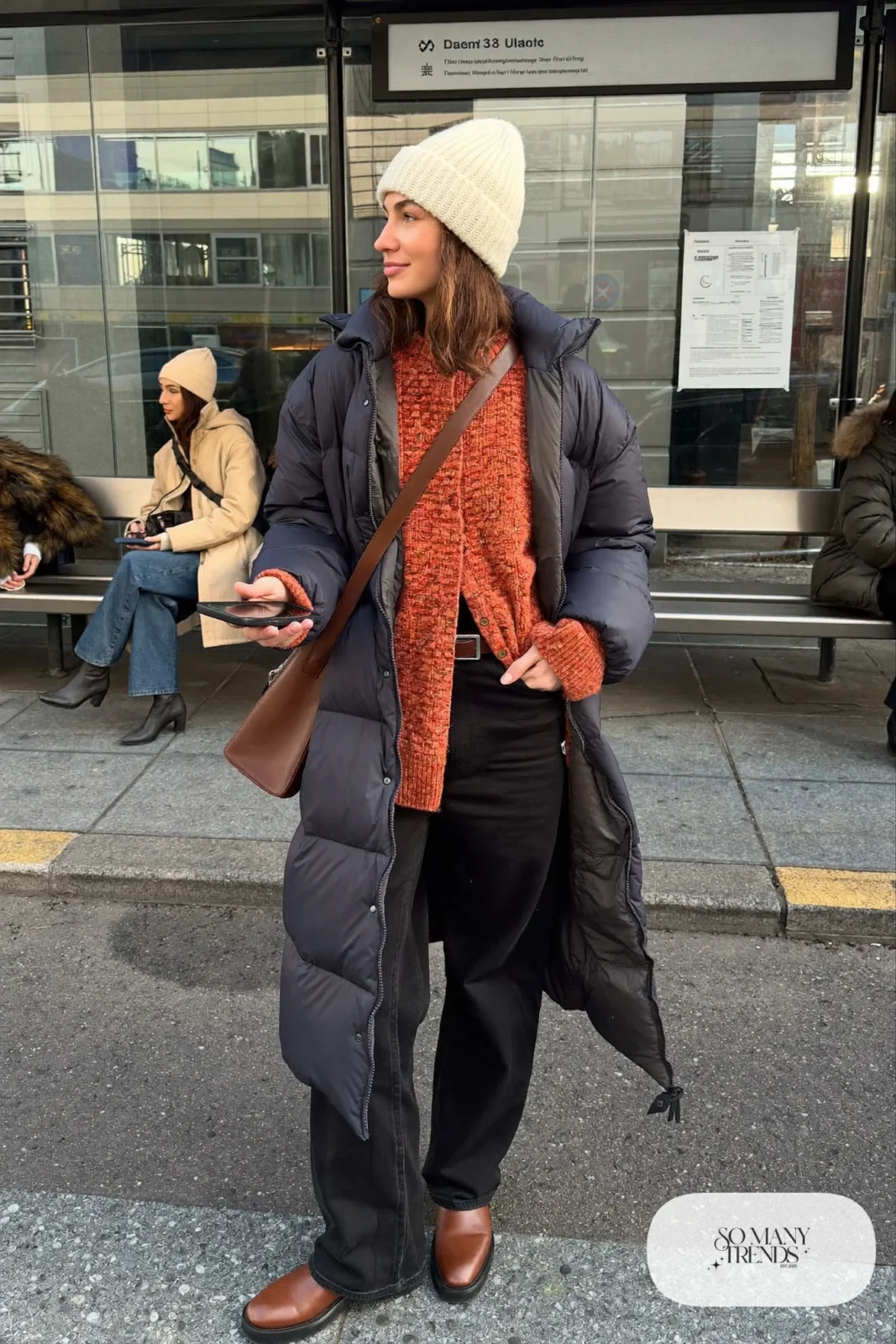 navy long puffer coat rust orange knit sweater black jeans brown boots cream beanie brown bag outfit 25