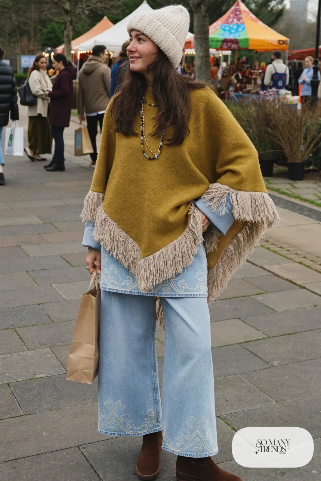 mustard fringe poncho embroidered denim jacket flared jeans brown boots beanie outfit 5