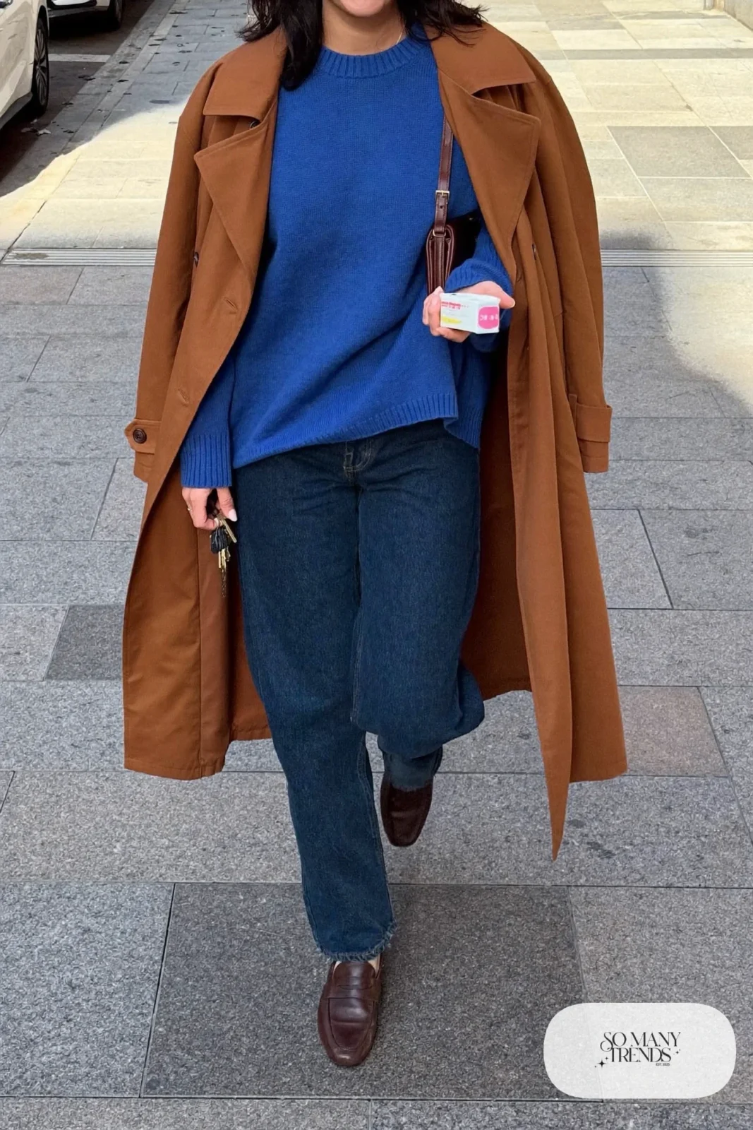 cobalt blue fine knit sweater, dark straight jeans, brown leather loafers, tan trench coat worn over shoulders outfit 7