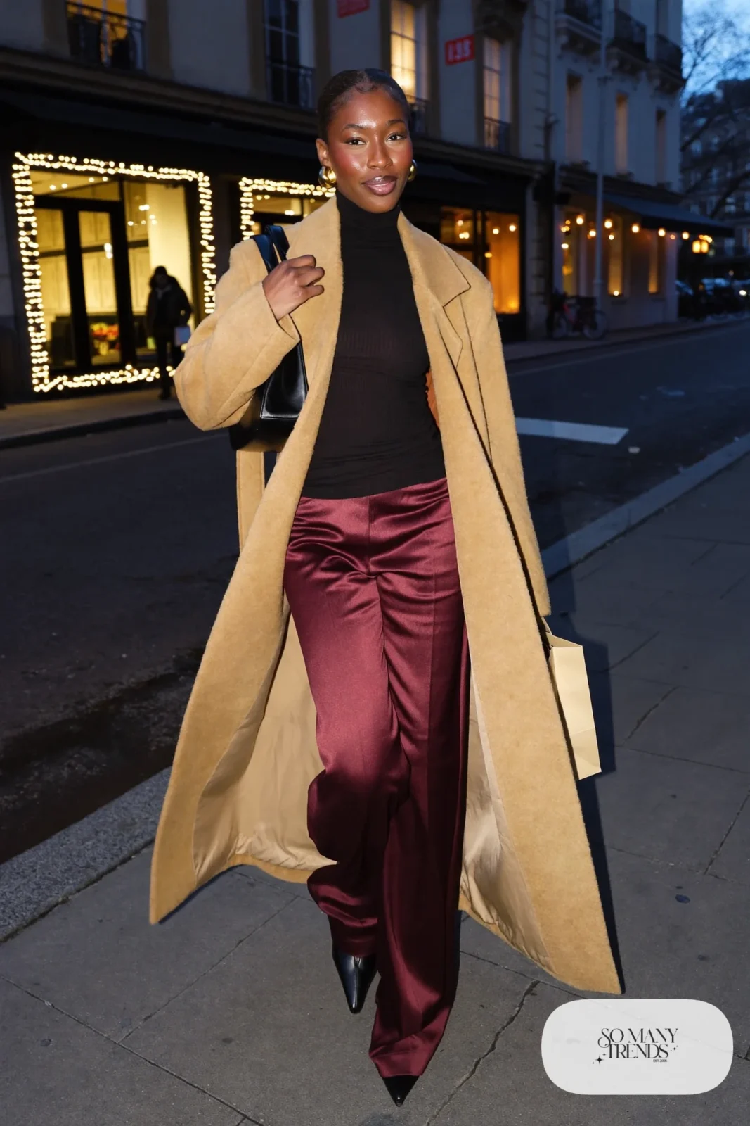 burgundy satin wide-leg pants fitted black knit top camel coat black boots gold hoops outfit 14