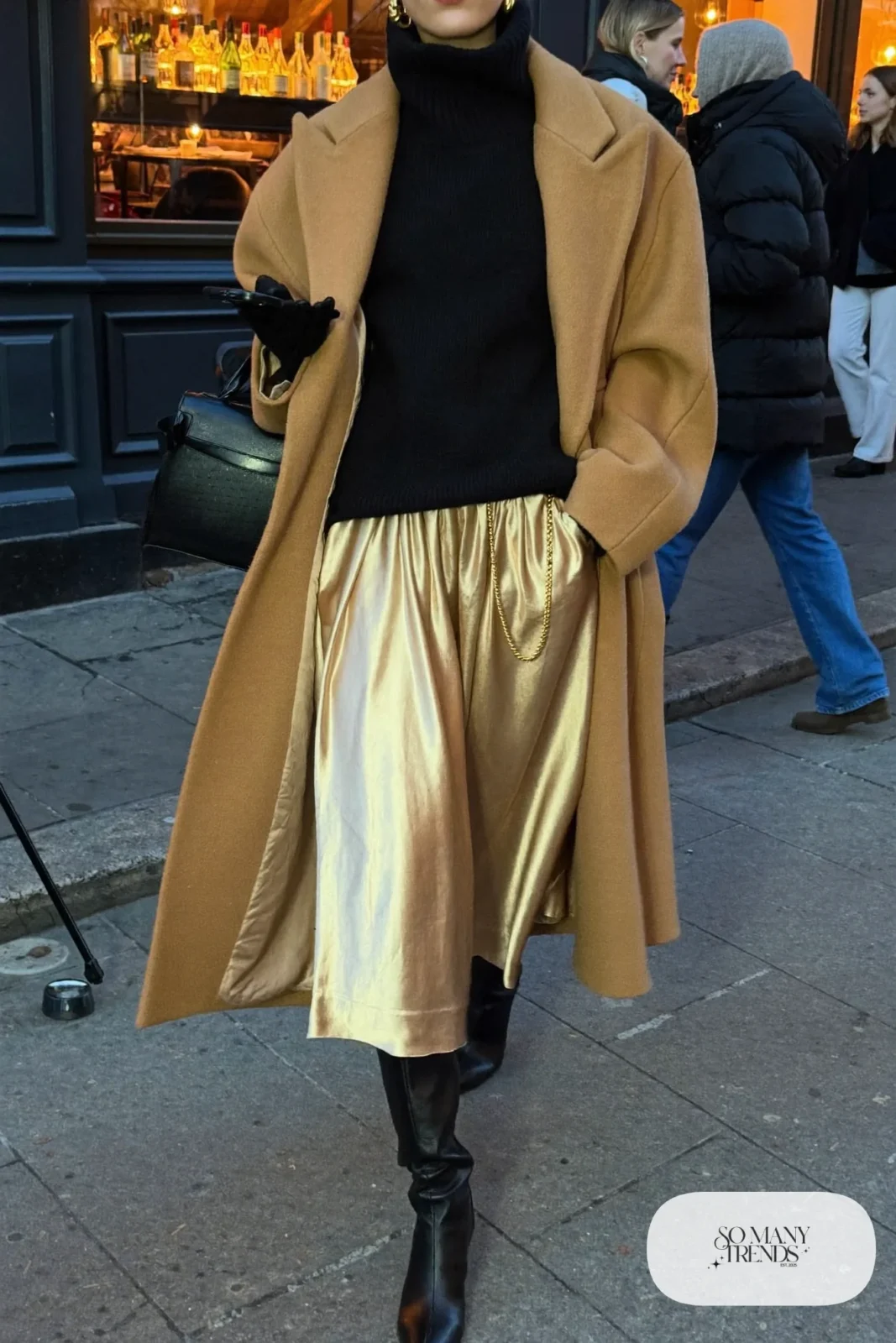 champagne satin pleated midi skirt black chunky turtleneck camel wool coat black knee-high boots gold chain outfit 21