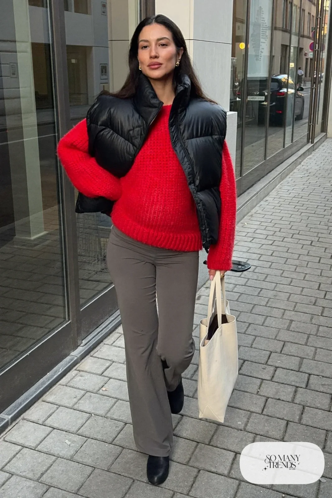 pregnant woman in cherry red knit sweater, gray maternity pants, black puffer vest and black ankle boots, outfit 6