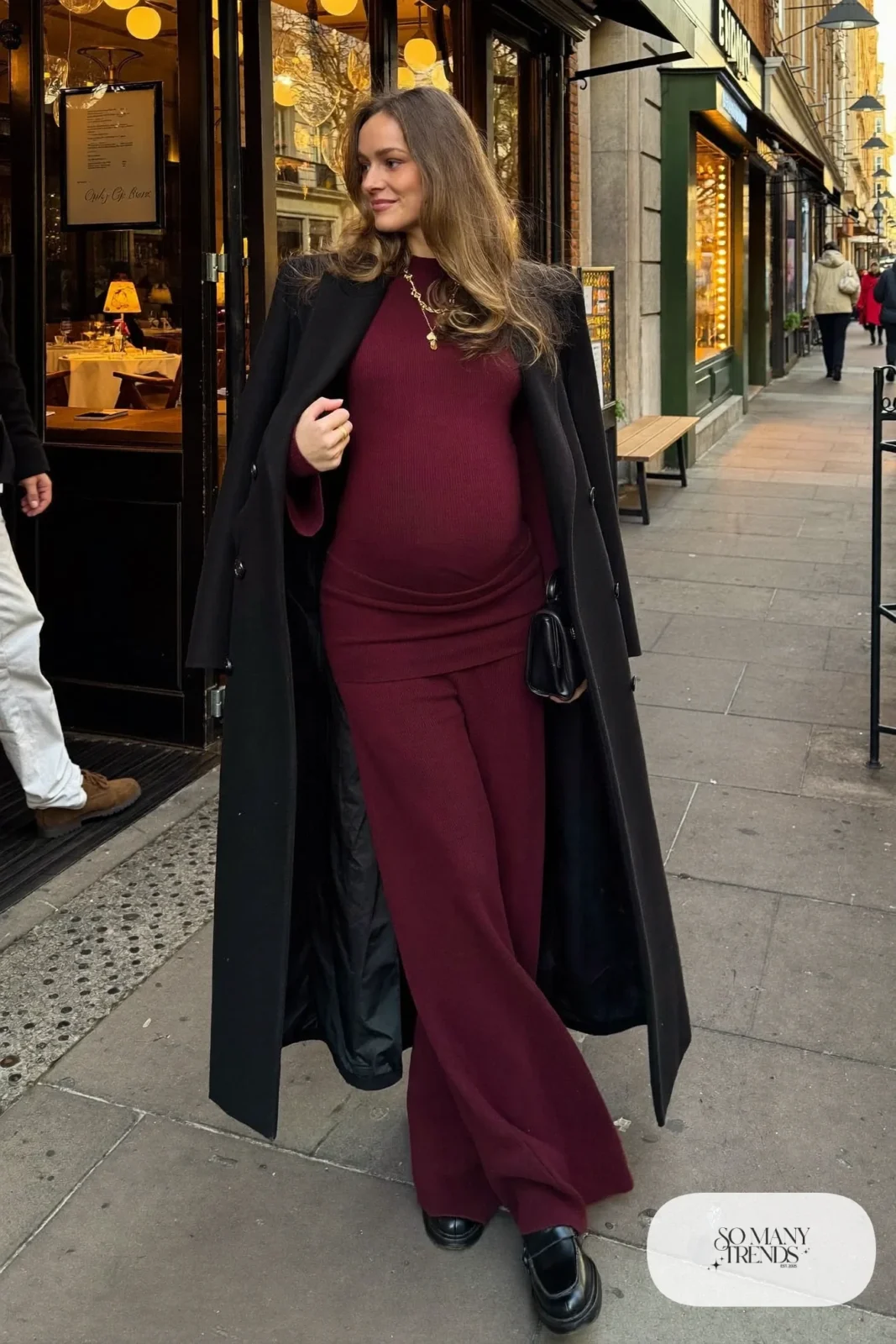 pregnant woman in burgundy ribbed knit two-piece set, black wool coat, black loafers and gold necklace, outfit 22