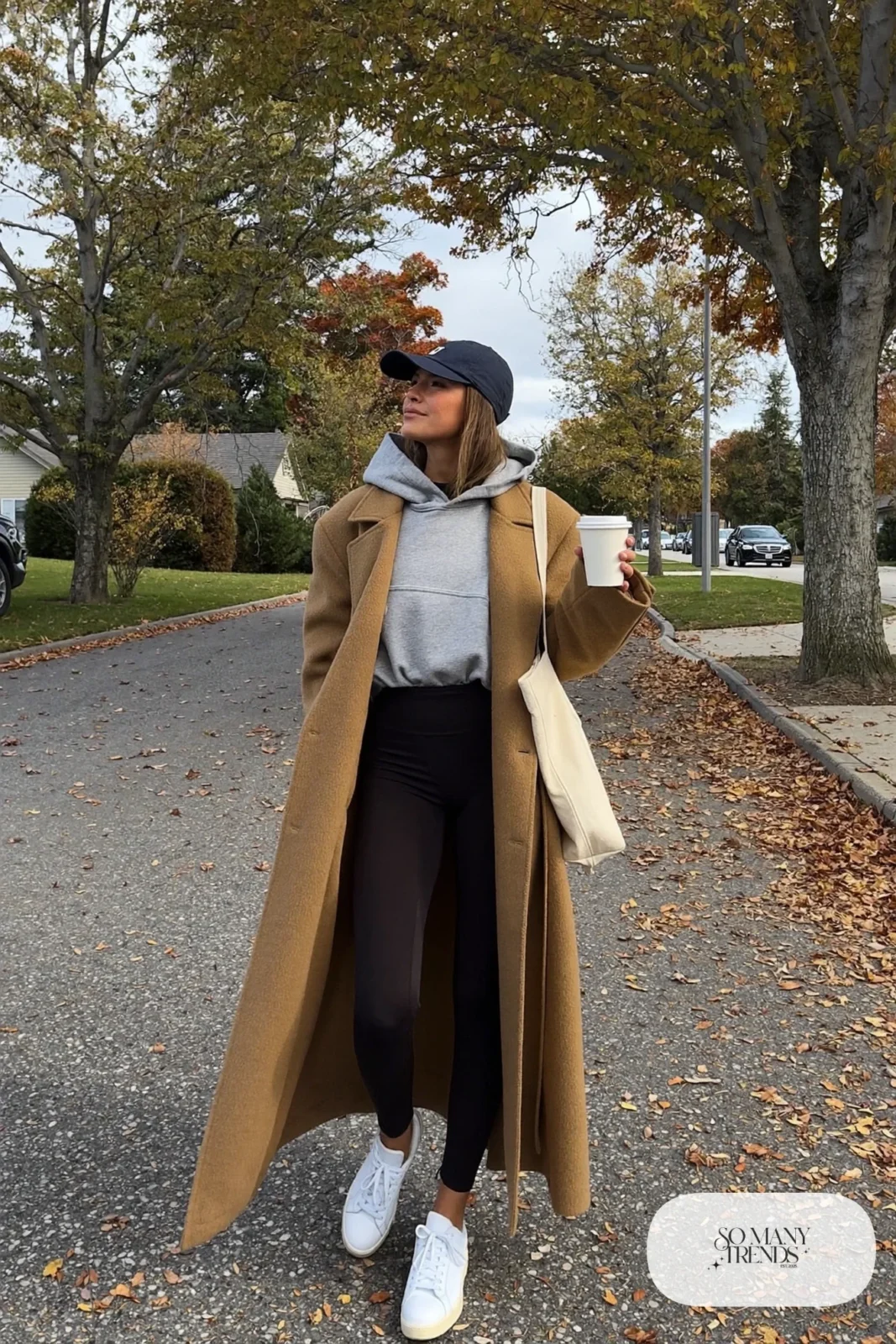 long camel wool coat gray hoodie black leggings white sneakers baseball cap tote outfit 6