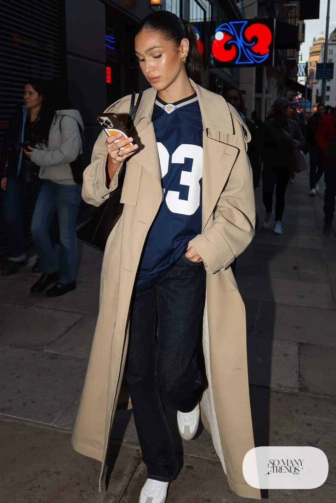 navy football jersey long beige trench coat dark jeans white sneakers outfit 9