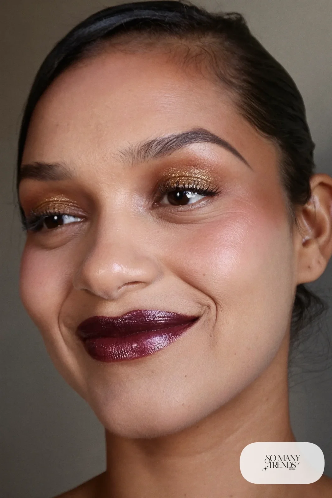 woman with deep plum satin lipstick, glowing bare skin and defined brows, winter makeup look 2