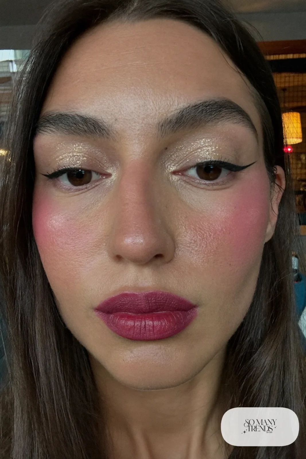 woman with brick red lipstick, gold shimmer on the lids and a thin wing, winter makeup look 9