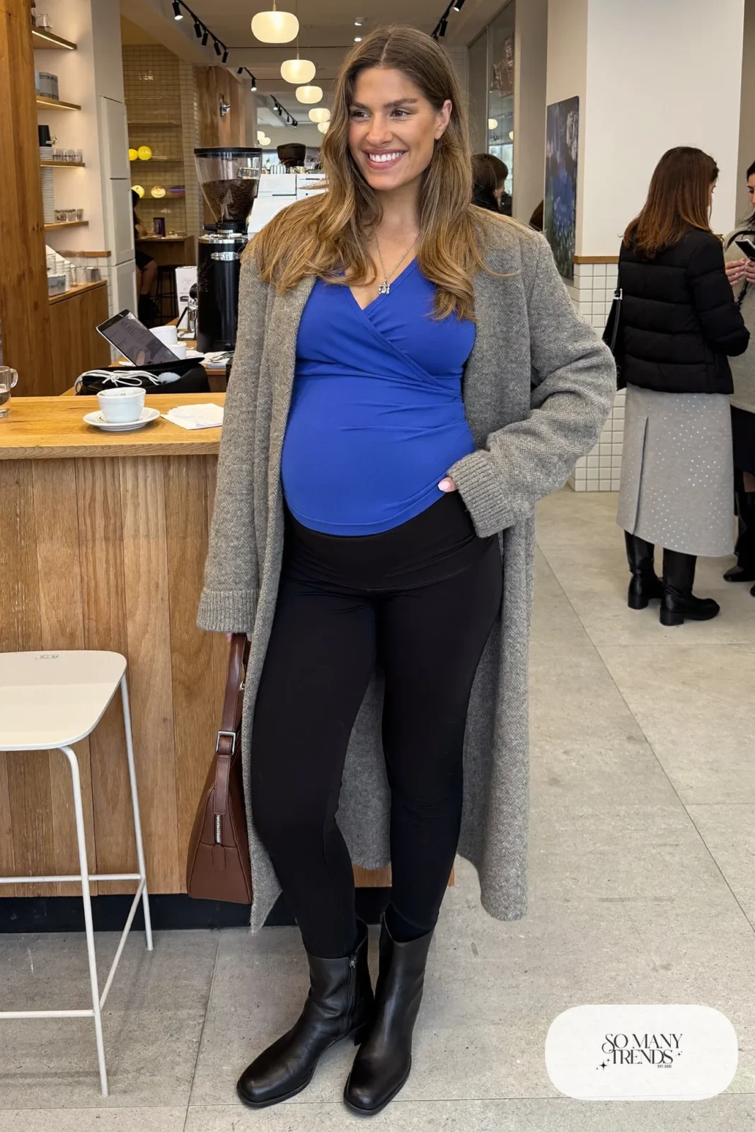 pregnant woman in cobalt blue wrap top, black maternity pants, long gray cardigan and ankle boots, outfit 3