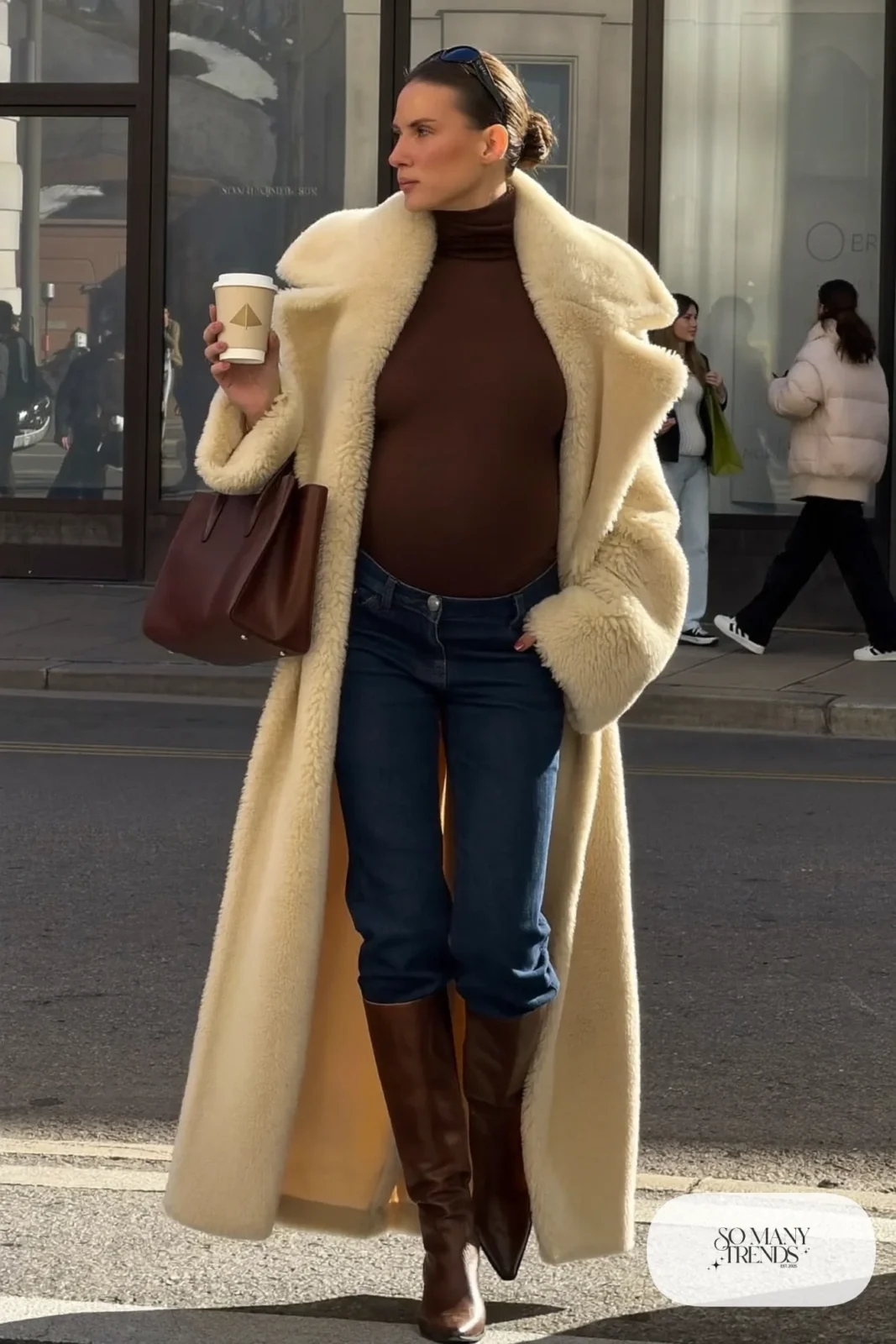 pregnant woman in cream shearling coat, chocolate turtleneck, dark maternity jeans and brown tall boots, outfit 27