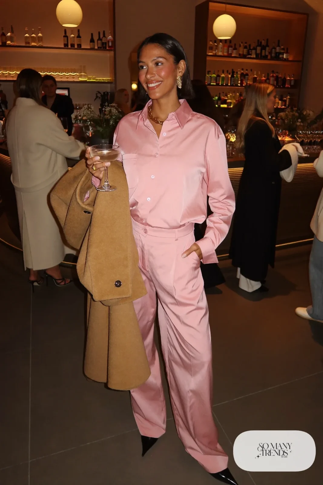 pink satin button shirt and matching pants set pointed black heels gold jewelry long camel coat outfit 23