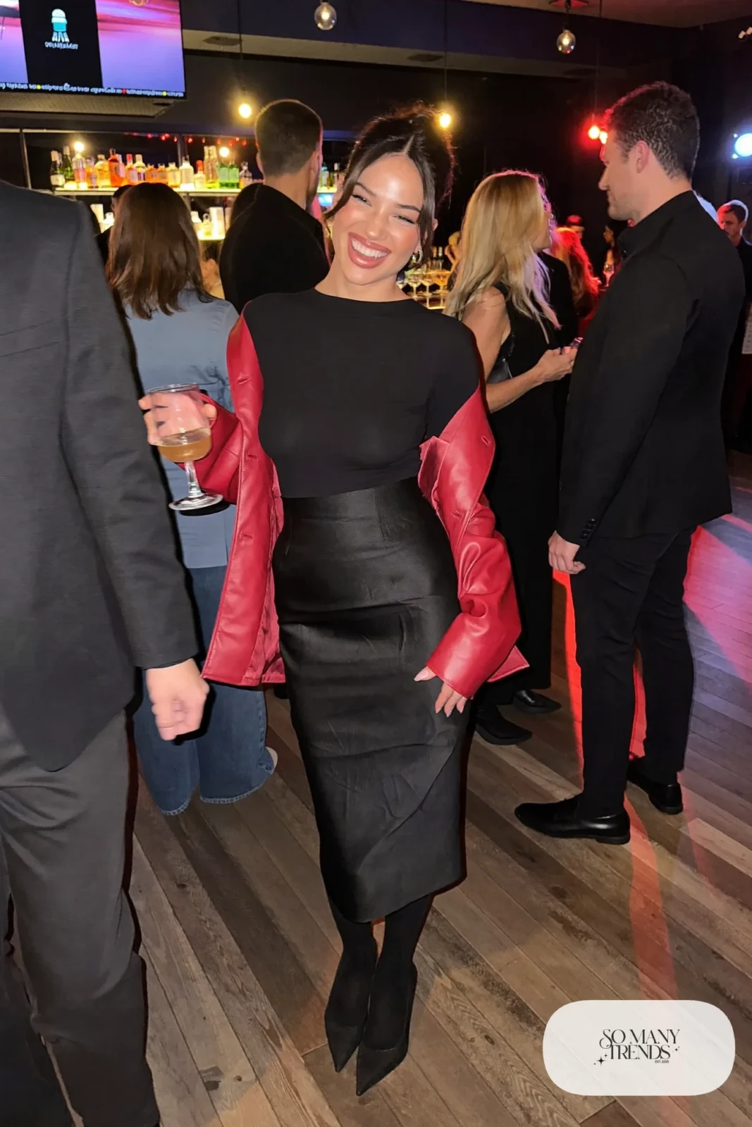 black satin midi skirt fitted black long-sleeve top red faux leather jacket sheer tights black pumps outfit 25