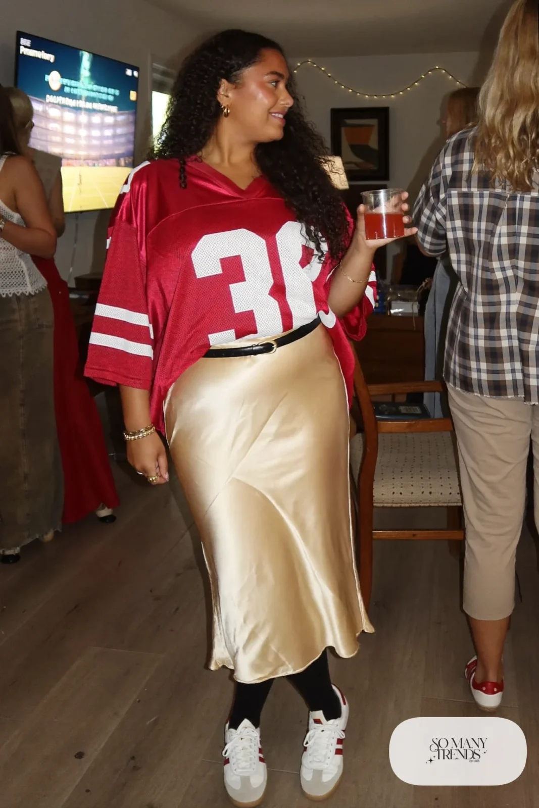 oversized red football jersey champagne satin midi skirt black tights white sneakers leather belt outfit 1