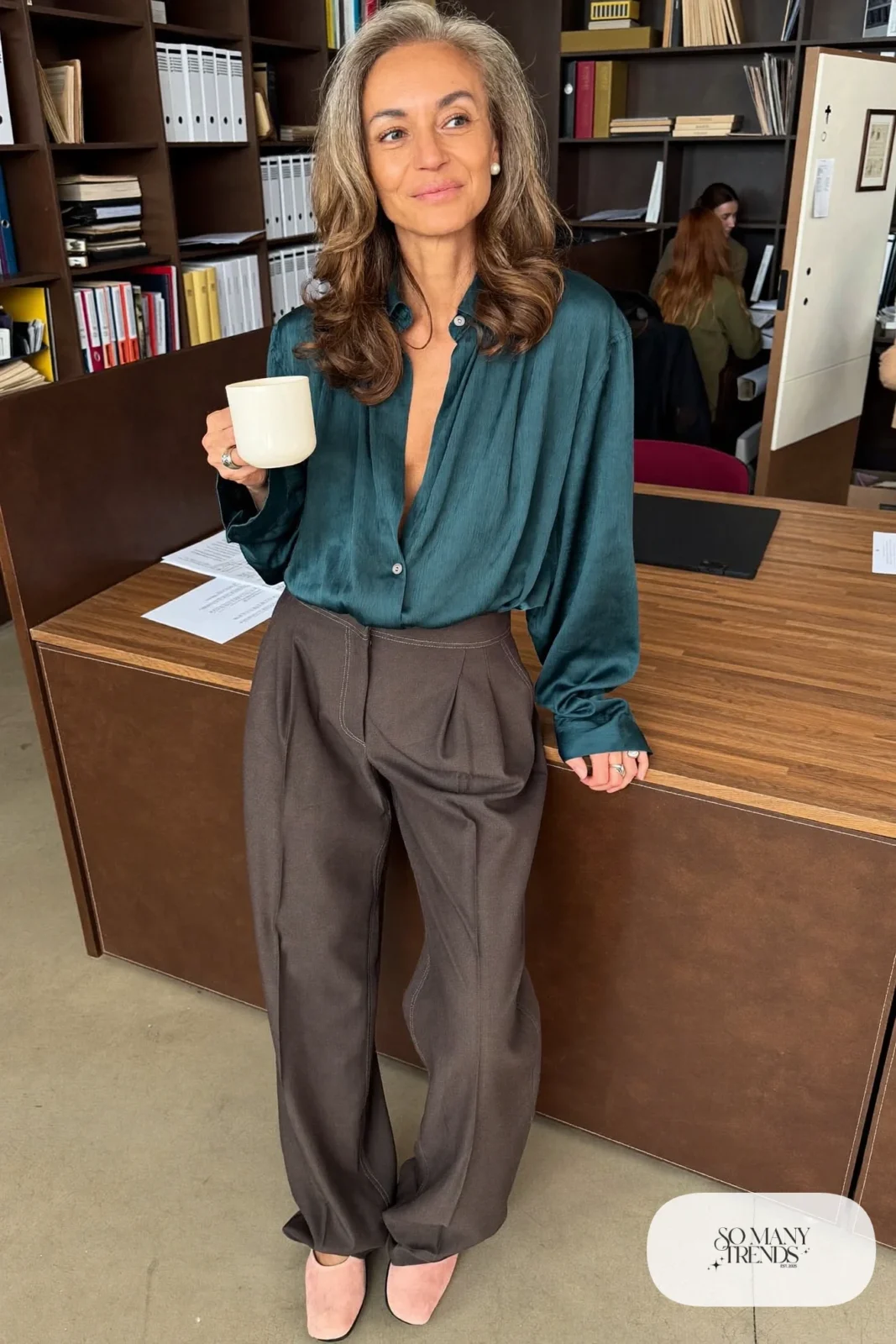 Woman in her fifties in a teal drapey blouse, charcoal wide-leg pants and pale pink flats, outfit 5