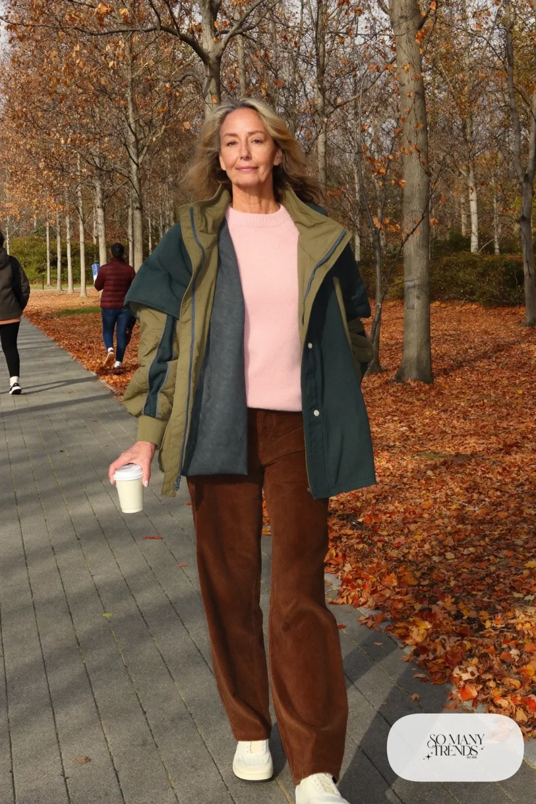 Woman in her fifties in wide-leg espresso corduroy pants, pale pink sweater, olive quilted jacket and sneakers, outfit 9