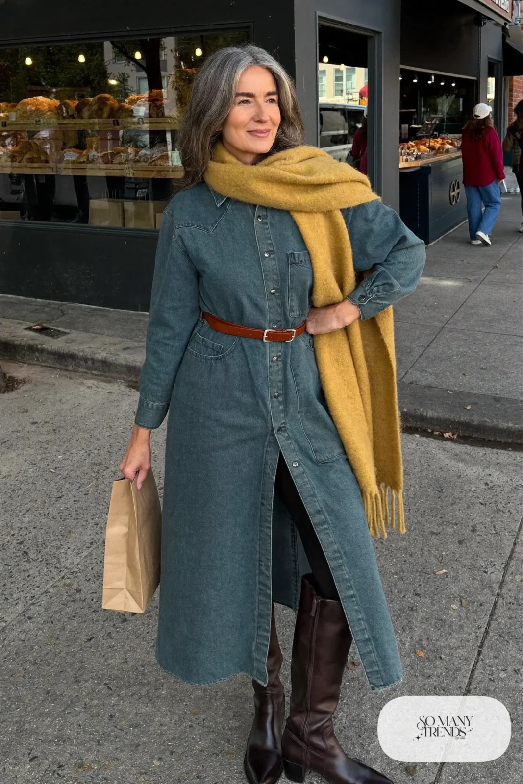 Woman in her fifties in a long denim shirt dress, belt, sheer black tights and tall espresso boots, outfit 10