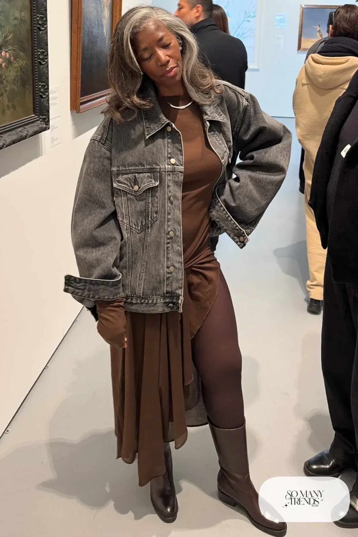 Woman in her fifties in an espresso midi dress, boxy denim jacket, tights and tall boots, outfit 19