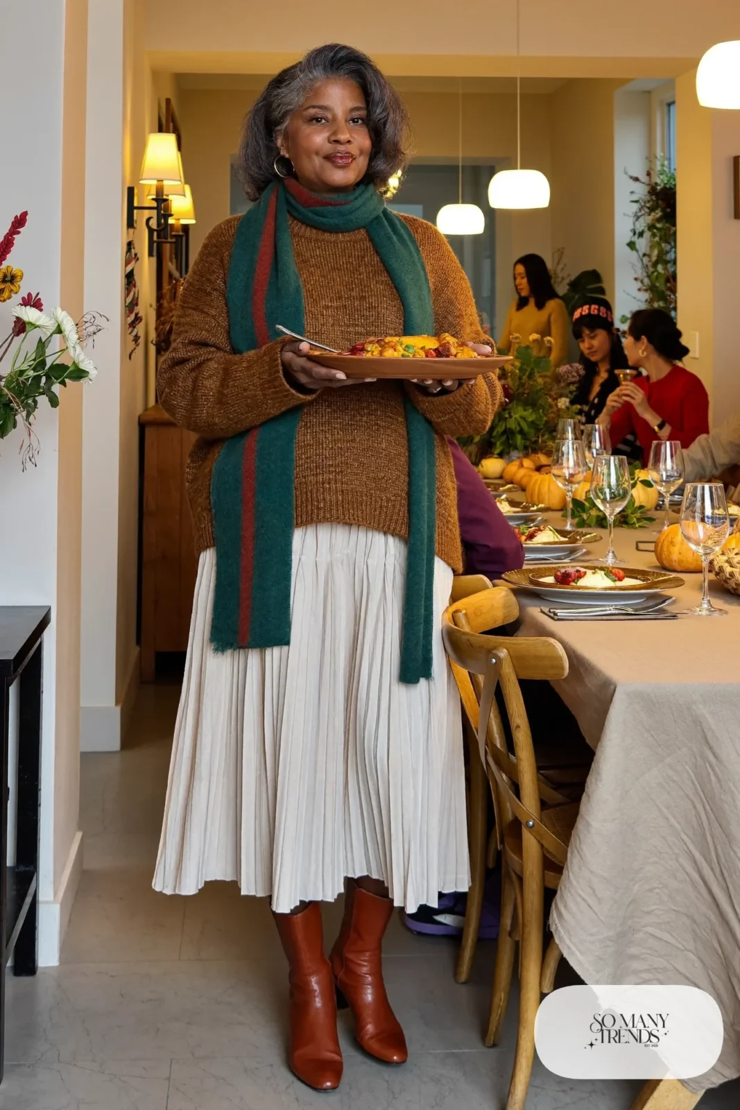 Woman in her fifties in an espresso sweater, ivory pleated midi skirt, tights and flat ankle boots, outfit 28