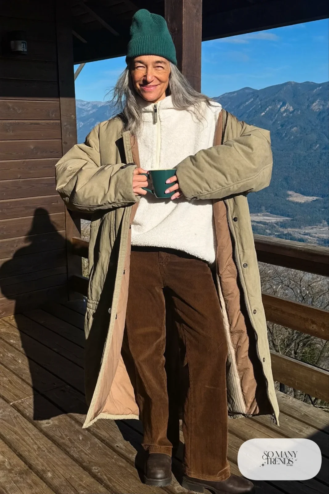 Woman in her fifties in a cream fleece pullover, espresso corduroy pants, lug-sole boots and a teal beanie, outfit 33