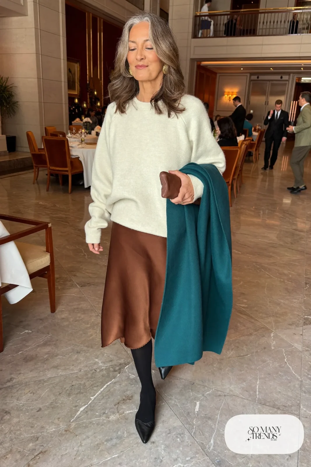 Woman in her fifties in an espresso satin midi skirt, ivory sweater, sheer tights and pointed flats, outfit 35