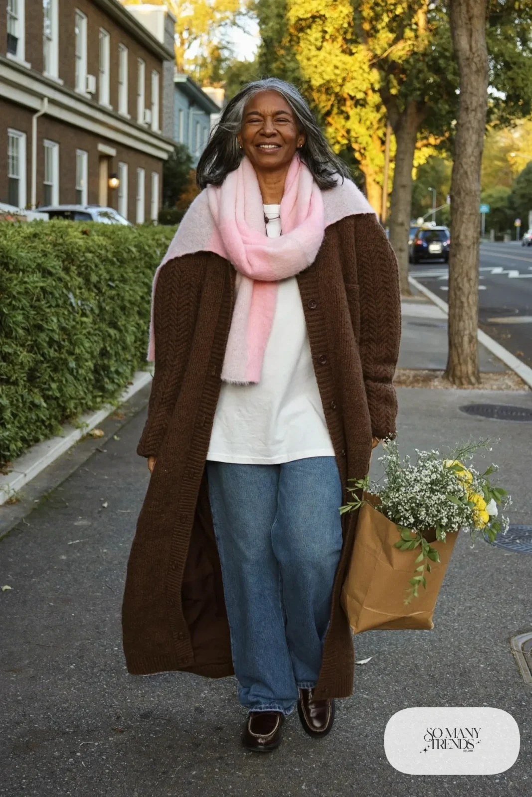 Woman in her fifties in a long espresso cardigan coat, white tee, relaxed jeans, pink scarf and loafers, outfit 36
