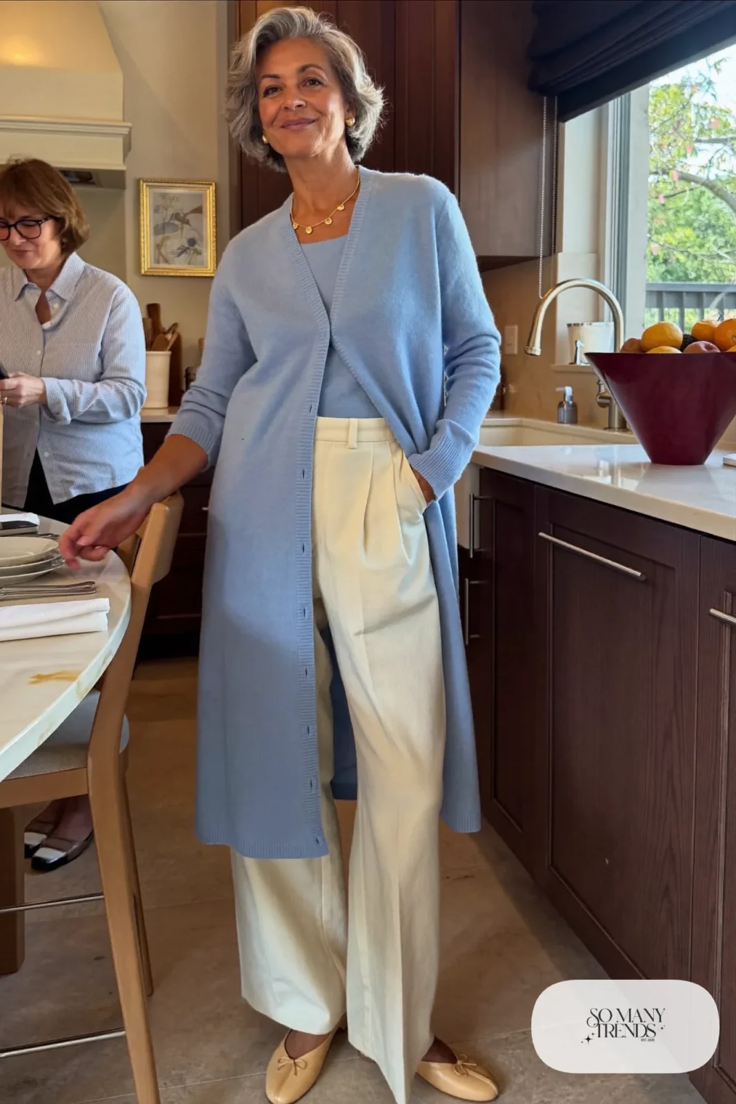 Woman in her sixties wearing a powder blue knit cardigan with matching shell, cream wide-leg pants and cream ballet flats, outfit 6
