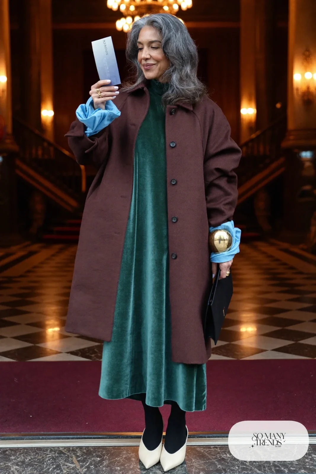 Woman in her sixties wearing a forest green velvet maxi dress under a long chocolate wool coat with cream pointed pumps, outfit 21