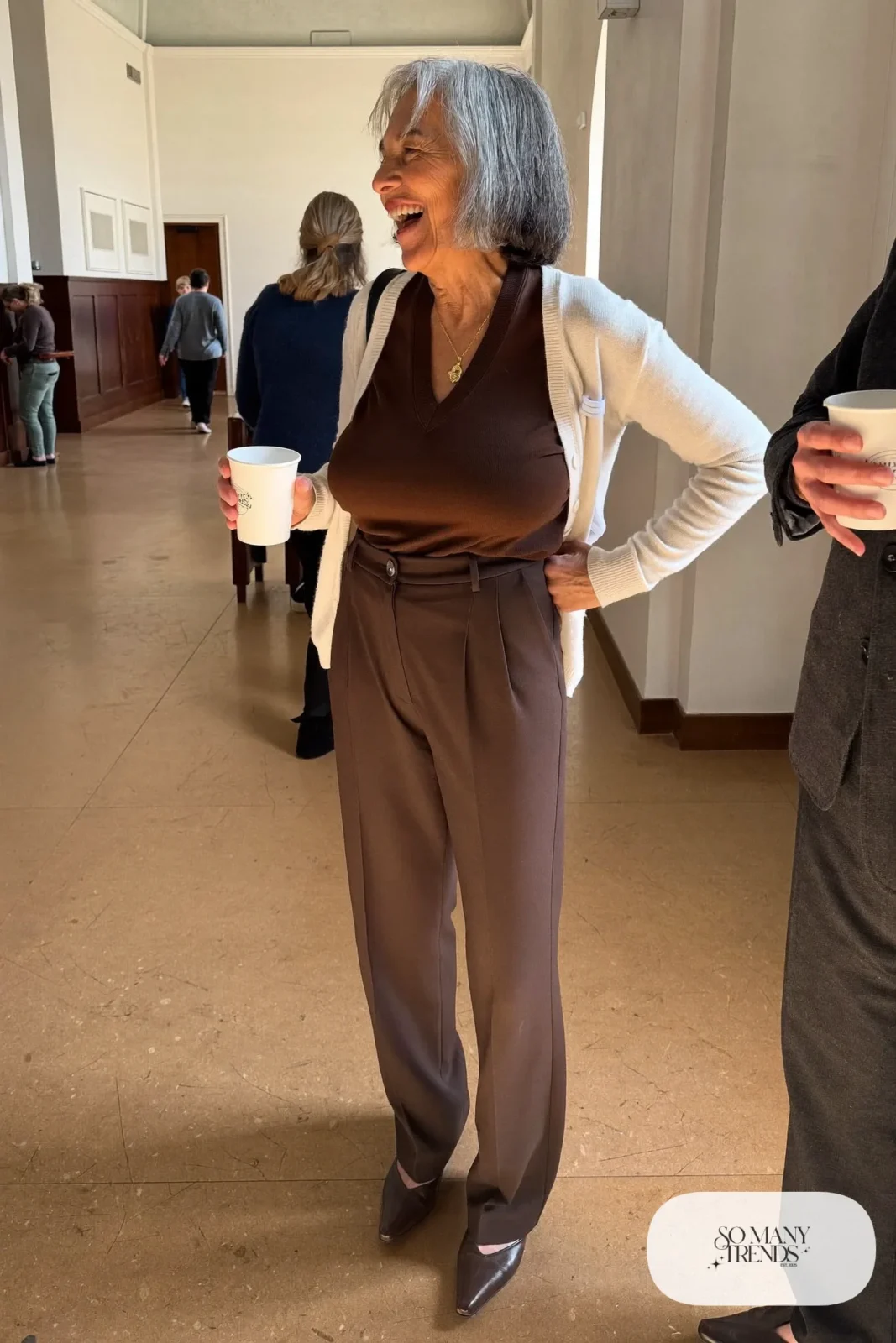 Petite woman in a hip-length cream cardigan over a chocolate knit top and straight brown pants, outfit 4
