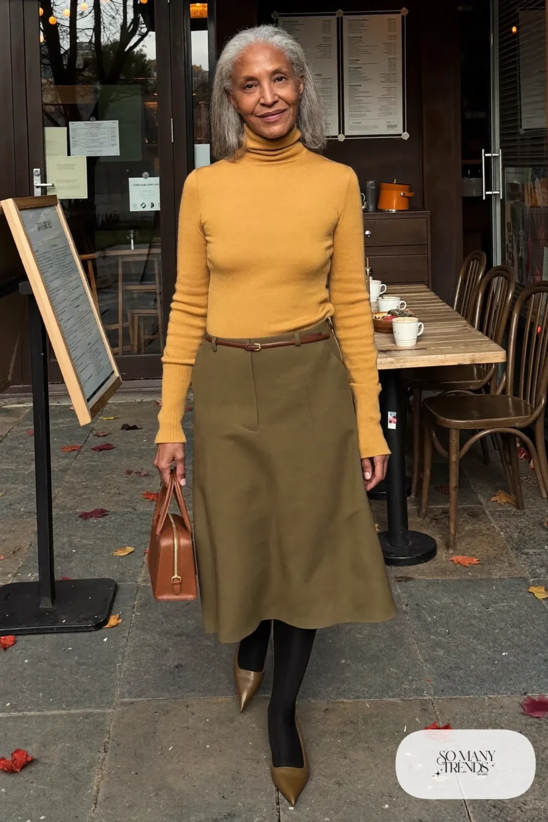 Petite woman in an olive midi skirt with a tucked mustard turtleneck and pointed flats, outfit 5