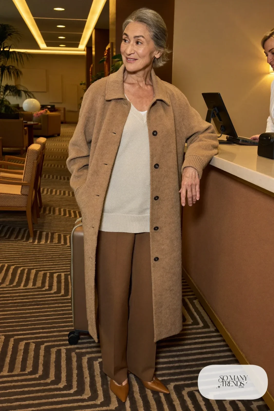 Petite woman in a knee-length camel cardigan coat over a cream knit and camel pants with pointed flats, outfit 21