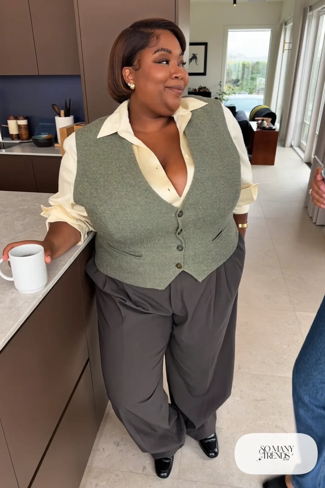 Woman in a sage knit vest over a cream silk shirt with charcoal wide-leg pants and loafers, outfit 20