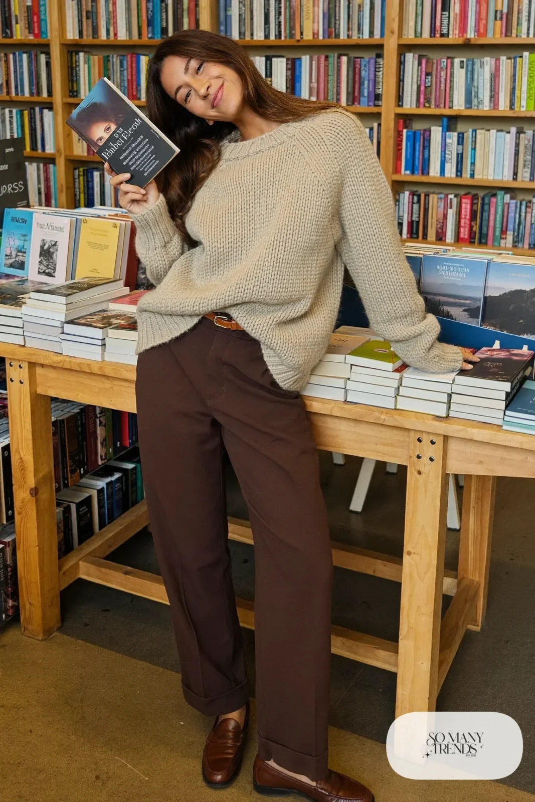 Woman with a straight athletic figure in a cream chunky knit sweater tucked into chocolate brown trousers with a belt and loafers, outfit 4