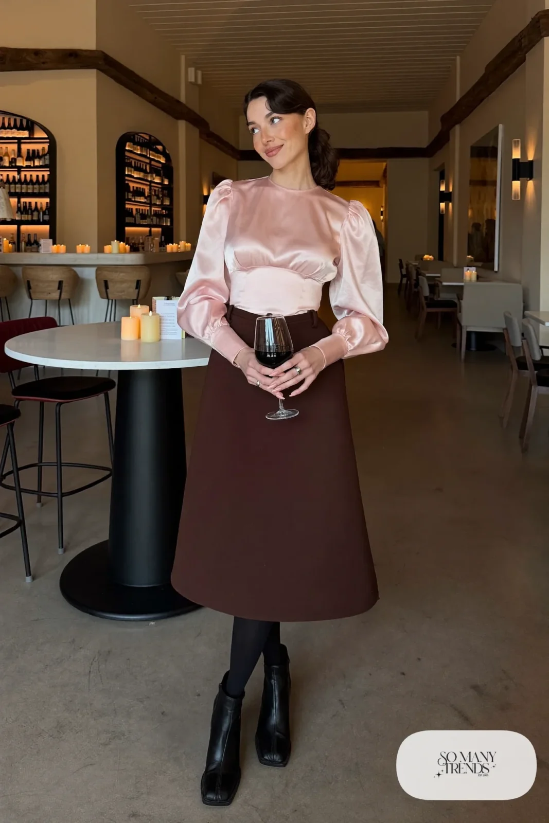 Woman with pear-shaped figure in a pale pink puff-sleeve blouse, espresso A-line midi skirt and black heeled boots, outfit 5
