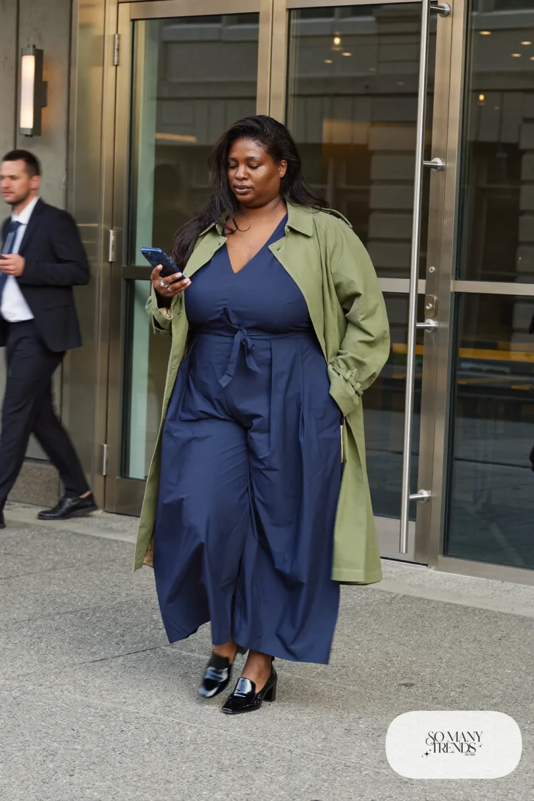 Woman in ink navy crepe wide-leg jumpsuit, open sage trench coat and black block-heel loafers, outfit 7