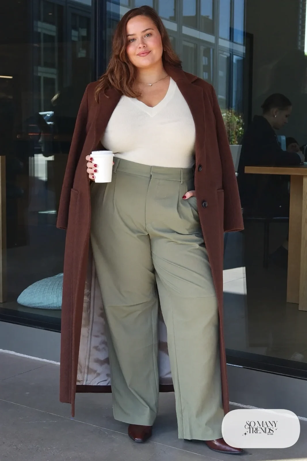 Woman in cream V-neck knit, sage twill straight pants, long espresso coat and brown ankle boots, outfit 24