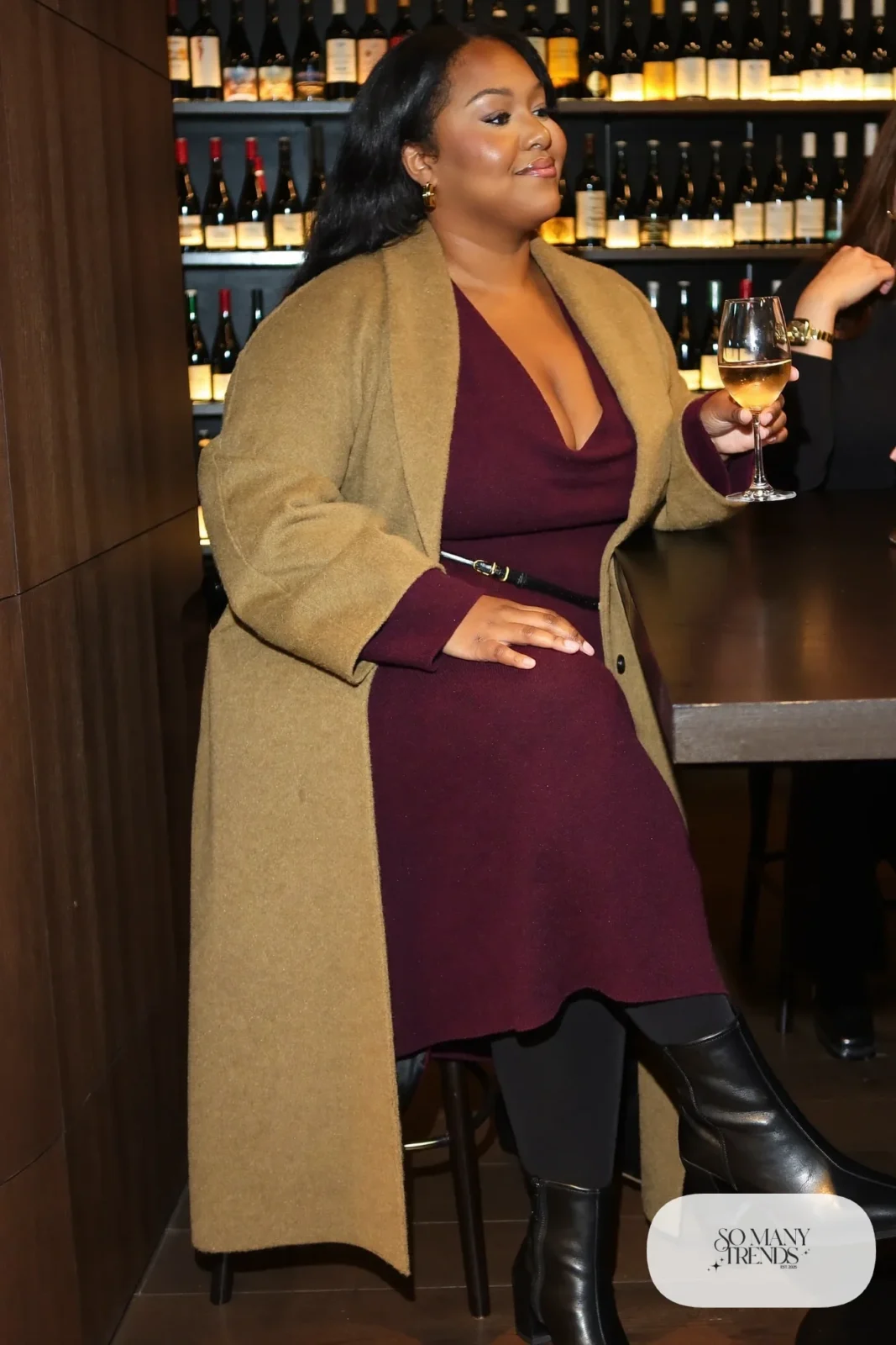 Woman in plum draped V-neck knit midi dress with belt, oatmeal long coat and block-heel boots, outfit 28