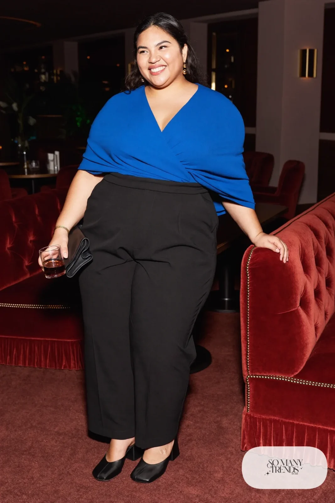 Plus size woman in cobalt draped top with black wide-leg pants and black block-heel mules, outfit 7