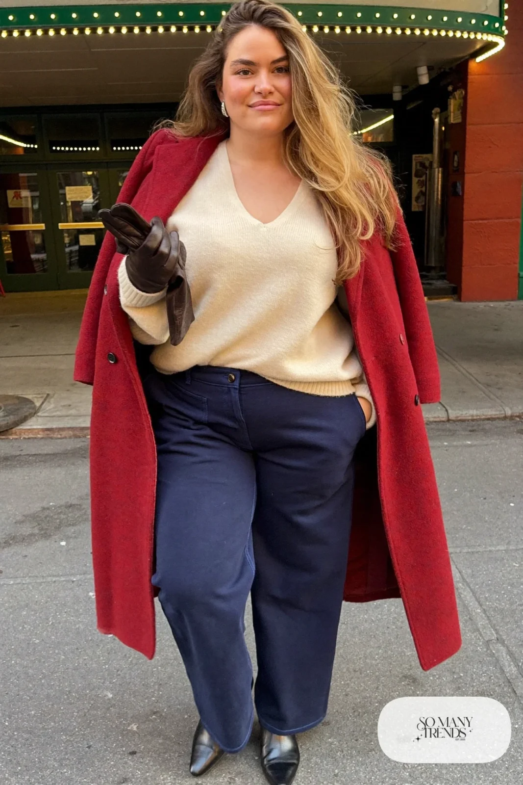 Plus size woman in oxblood long coat, ivory sweater, navy pants and black ankle boots, outfit 26