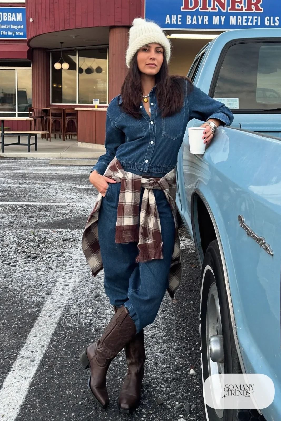 Indigo long-sleeve denim jumpsuit, flannel shirt tied at waist, cream beanie and brown cowboy boots, outfit 19