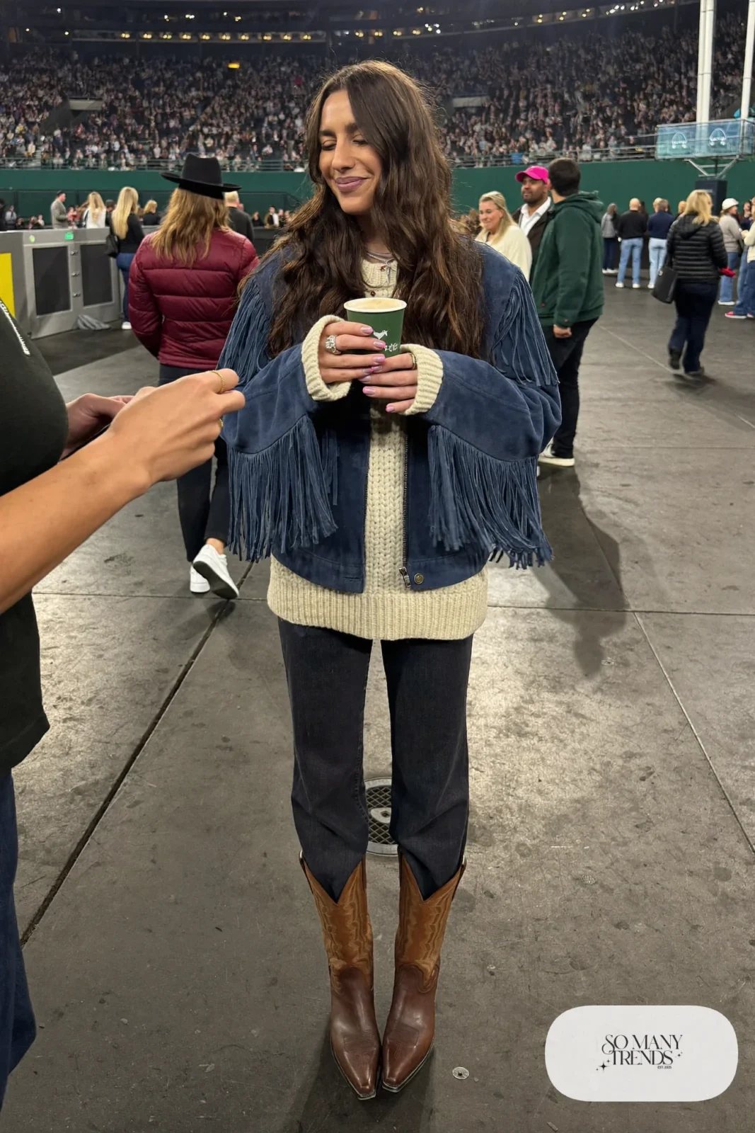 Woman in ink blue suede fringe jacket, cream knit, dark straight jeans and chocolate cowboy boots, NFR outfit 1