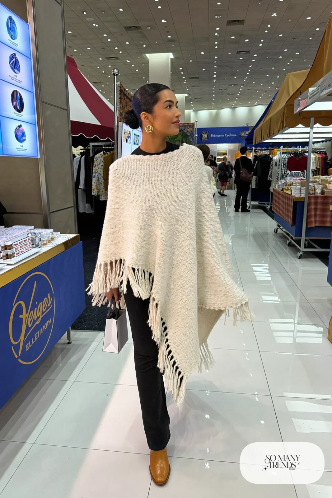 Woman in cream fringe poncho, black fitted tee, black straight pants and cognac boots, NFR outfit 9
