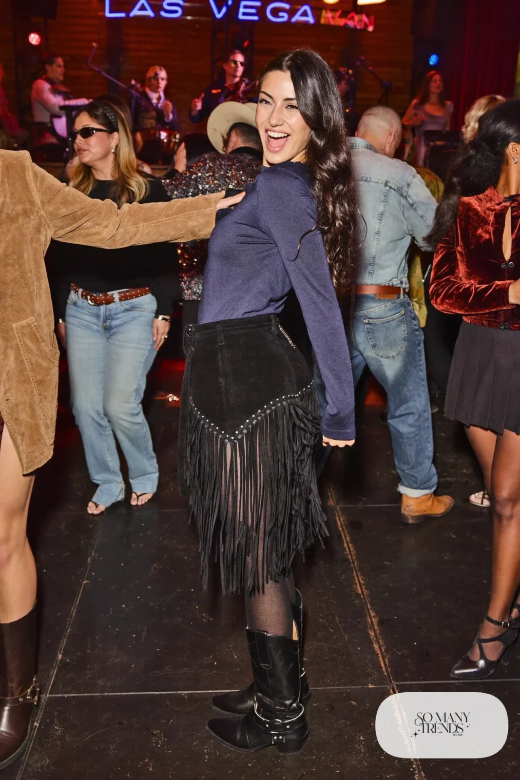 Woman in black fringe midi skirt, ink blue fitted long-sleeve top, sheer tights and black boots, NFR outfit 15