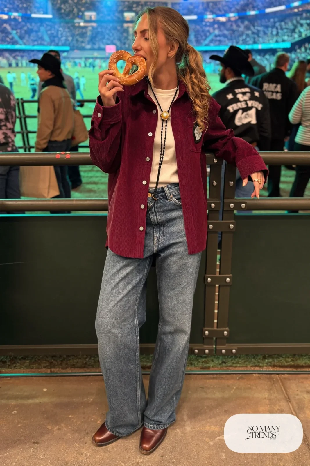 Woman in burgundy corduroy shirt jacket, cream tee, mid-wash straight jeans and brown boots, NFR outfit 23