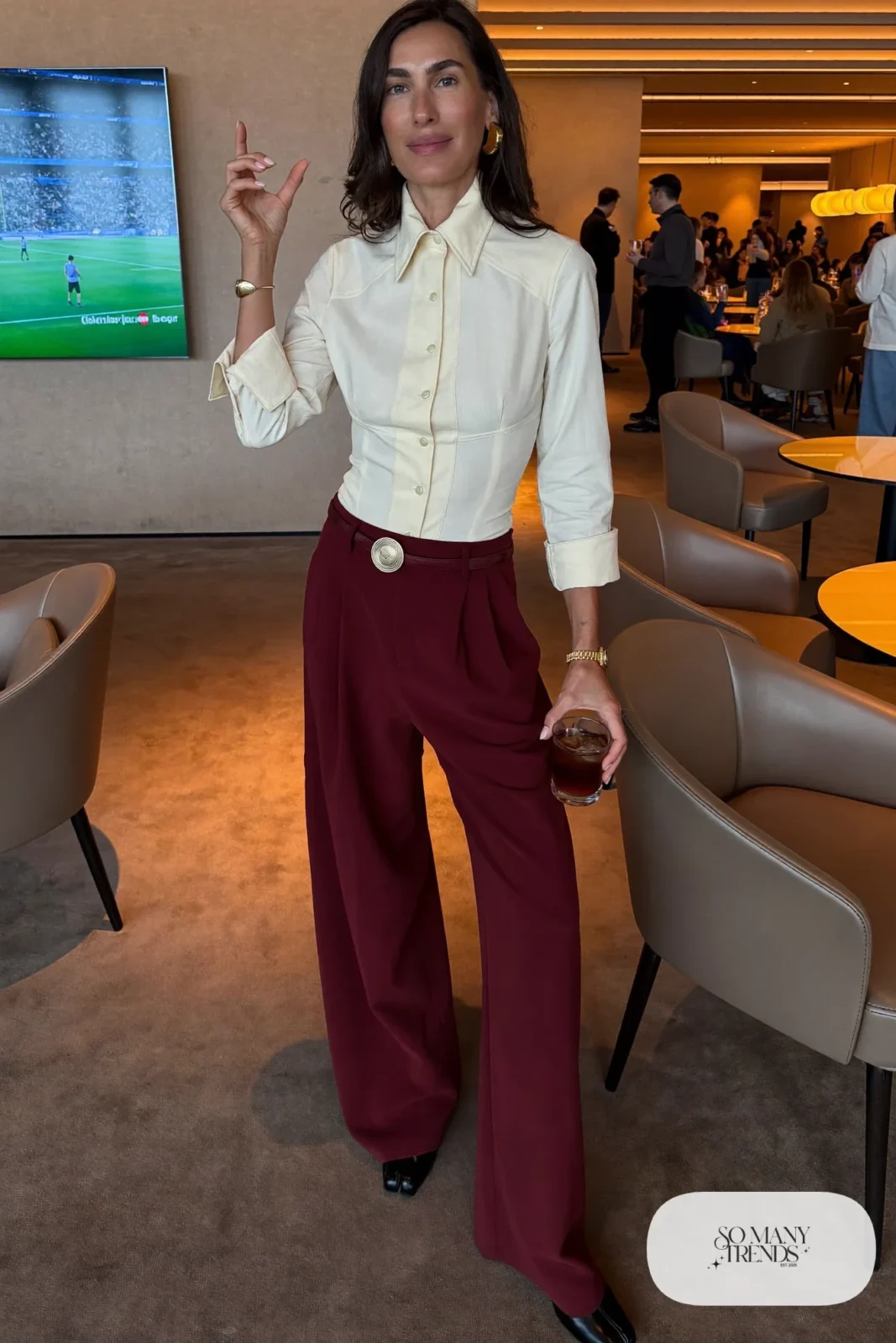 Woman in burgundy wide-leg pants, cream fitted top and black boots, outfit 24