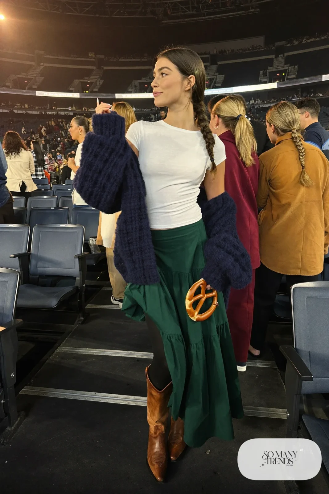Woman in a green tiered maxi skirt, navy chunky cardigan, white tee and cowboy boots, concert outfit 10