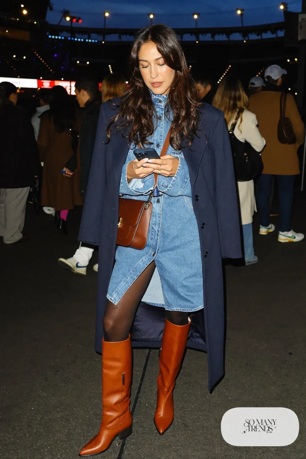 Woman in a denim western shirt dress, navy wool wrap coat, belt and tall cognac boots, concert outfit 25