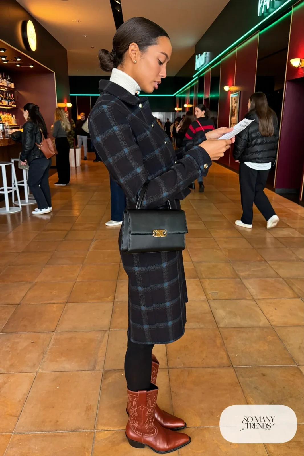 Woman in a navy plaid wool jacket and skirt, white turtleneck, black tights and cognac western boots, concert outfit 28
