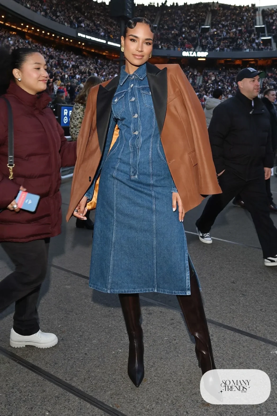 Woman in a tuxedo jacket worn over a denim midi dress with tall brown boots, concert outfit 29